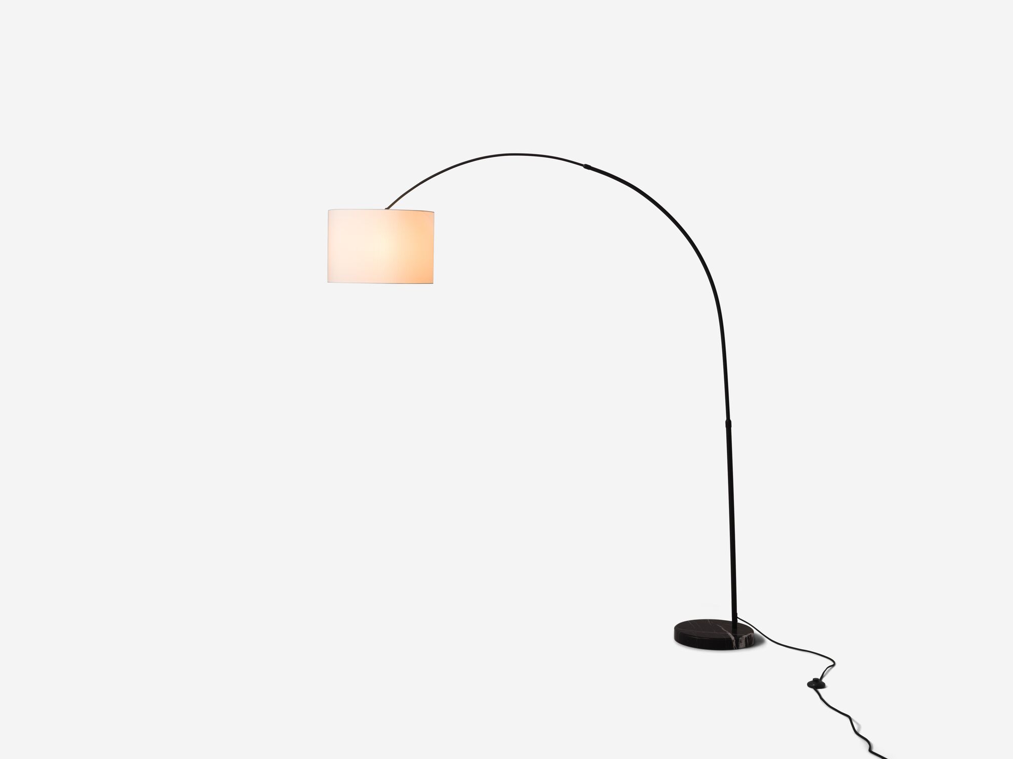 Side view of white arc floor lamp with light on